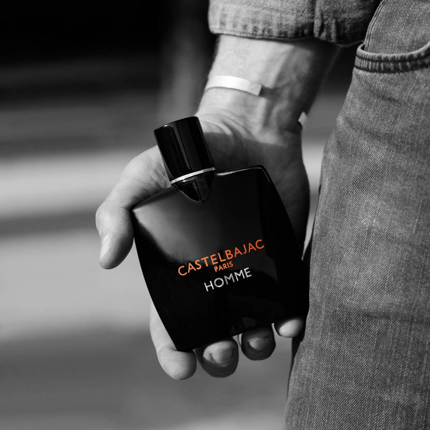 Castelbajac Paris HOMME Eau de Parfum bottle with sleek design and golden liquid, set against a backdrop of urban sophistication and citrus groves