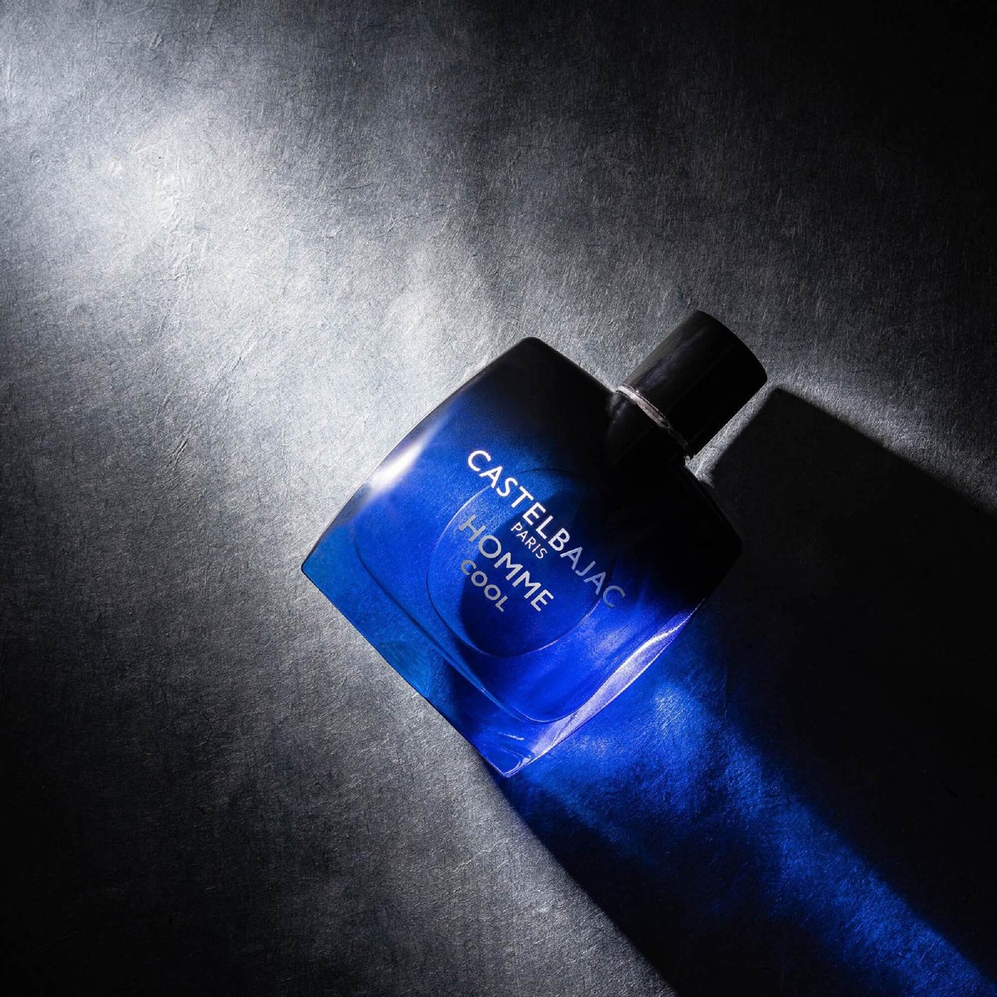 Castelbajac Paris HOMME COOL bottle with frost-blue liquid, set against rugged mountain terrain and icy alpine vistas