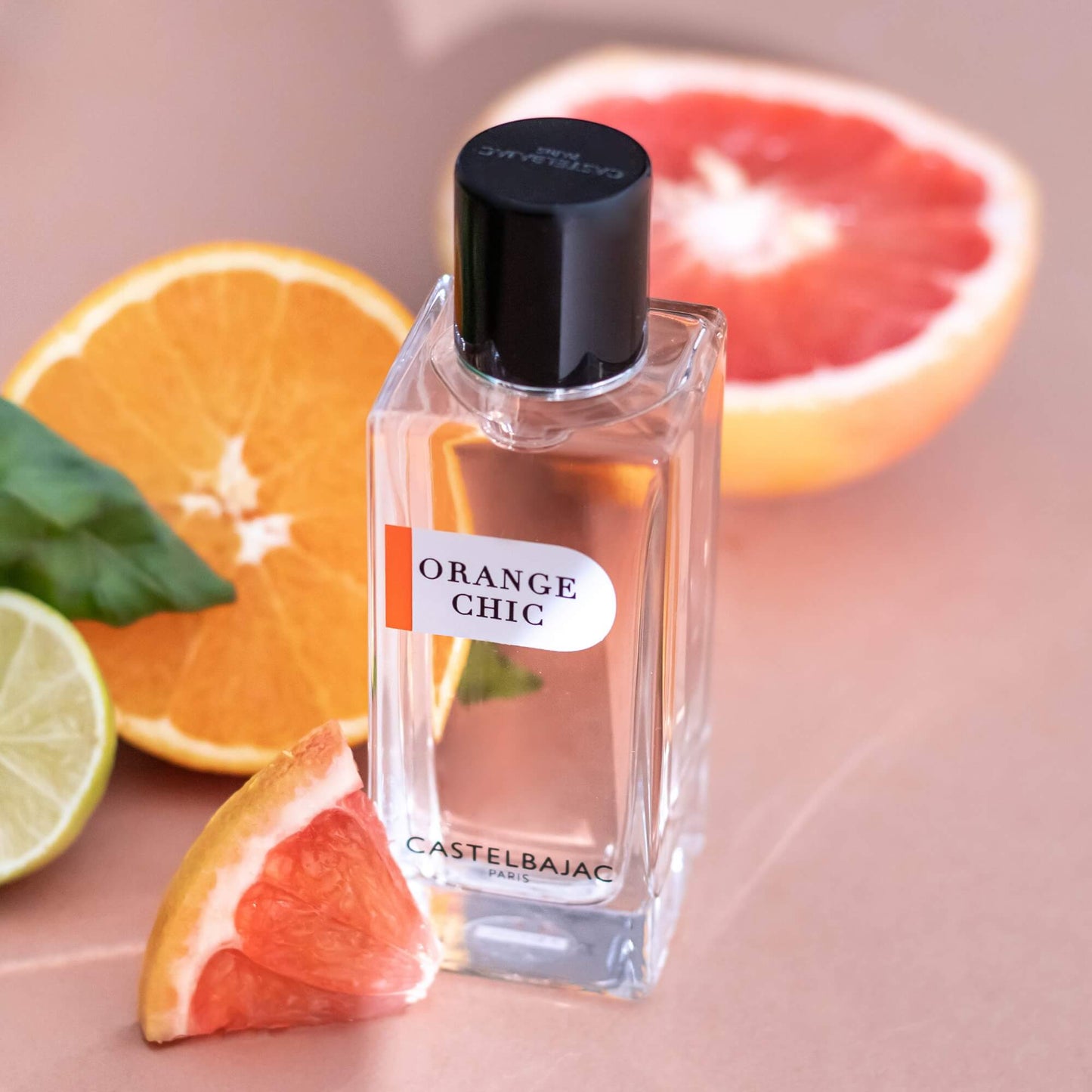 ORANGE CHIC Eau de Parfum bottle with vibrant orange liquid, glowing against a backdrop of Sicilian citrus groves and azure skies