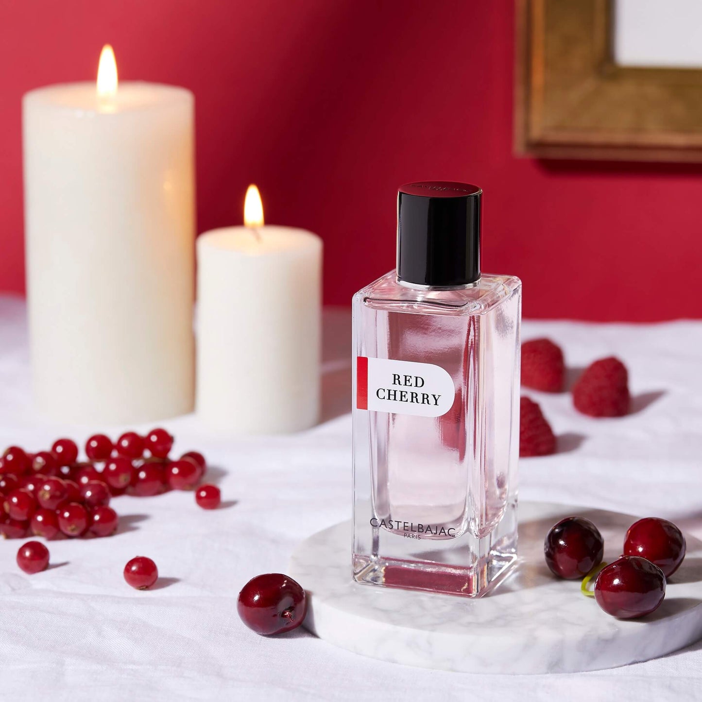 Castelbajac RED CHERRY perfume bottle with rich ruby liquid, glowing against a backdrop of cherries, pralines, and vanilla pods
