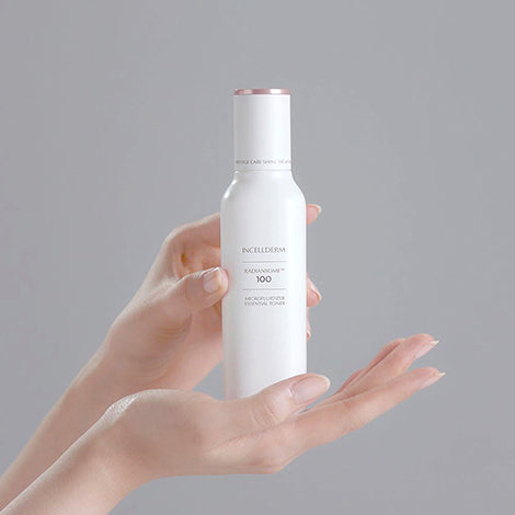 Radiansome™100 Microfluidizer Essential Toner bottle dispensing a clear liquid onto cotton pad, showcasing advanced skincare technology